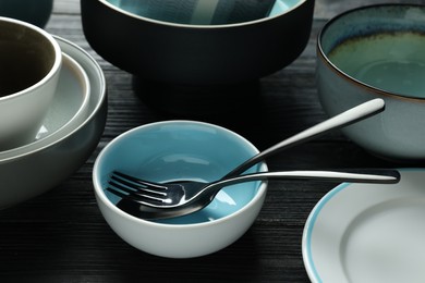Photo of Stylish empty dishware with cutlery on black wooden table
