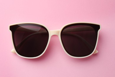 New stylish elegant sunglasses on pink background, top view