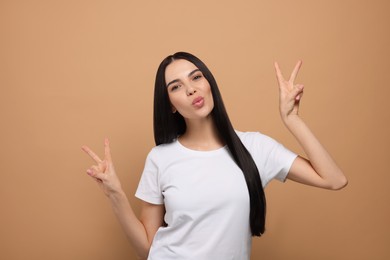 Photo of Beautiful young woman blowing kiss on beige background