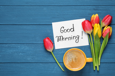 Message GOOD MORNING, tulips and coffee on blue  wooden table, flat lay. Space for text