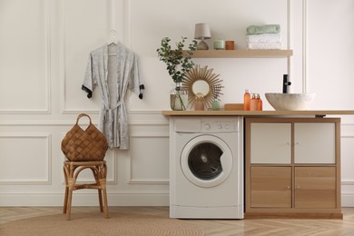 Laundry room interior with modern washing machine and stylish vessel sink on countertop