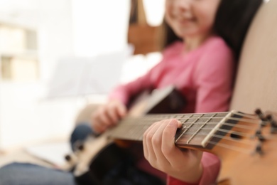 Little girl playing guitar at home, closeup. Learning music notes
