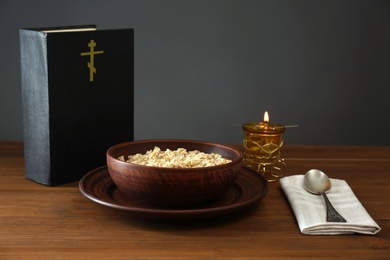 Bible, oatmeal porridge and spoon on wooden table. Lent season
