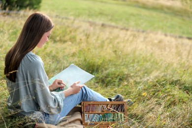 Young woman drawing with soft pastels in nature. Space for text