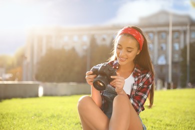 Young photographer with professional camera on green grass outdoors. Space for text