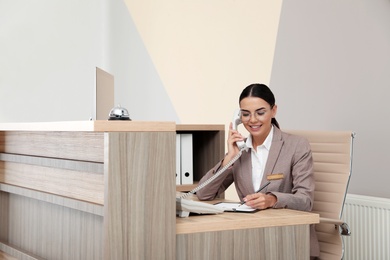 Receptionist talking on telephone at desk in modern hotel