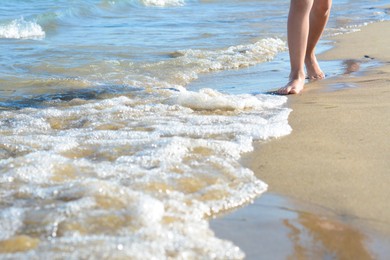 Photo of Child walking through water on seashore, closeup of legs. Space for text