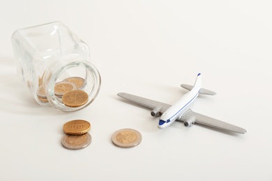 Toy plane, jar and coins on white background. Travel insurance
