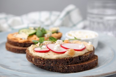 Photo of Delicious sandwiches with hummus and different ingredients on plate, closeup