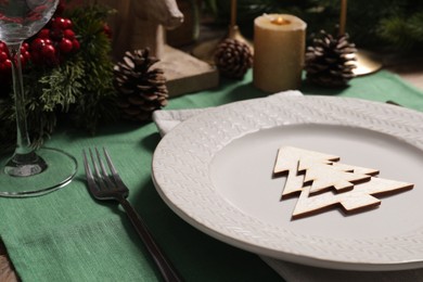 Photo of Festive place setting with beautiful dishware, cutlery and decor for Christmas dinner on wooden table, closeup