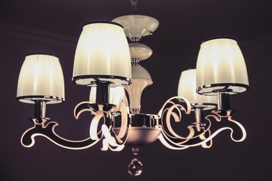 Photo of Stylish chandelier on ceiling in dark room