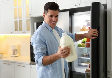 Man with gallon of milk near refrigerator in kitchen