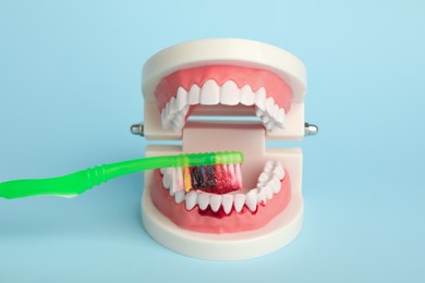 Photo of Jaw model and toothbrush with blood on light blue background. Gum inflammation