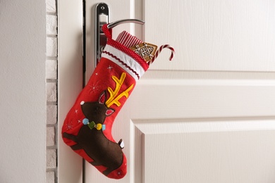 Stocking with presents hanging on door, space for text. Saint Nicholas Day tradition