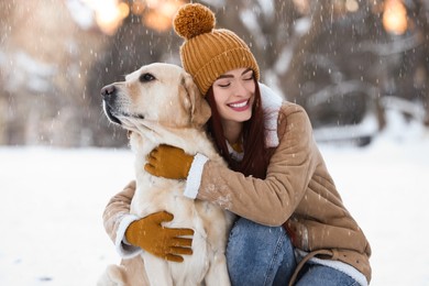 Photo of Beautiful young woman hugging cute Labrador Retriever on winter day outdoors