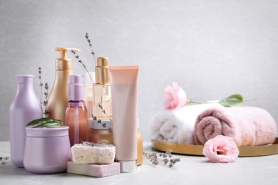 Set of hair cosmetic products and flowers on grey table