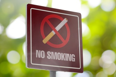 Sign No Smoking outdoors on sunny day. Bokeh effect