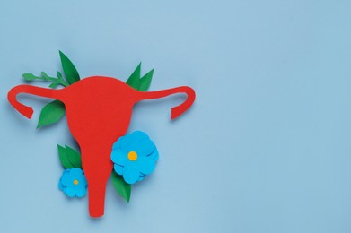 Photo of Woman's health. Paper uterus and flowers on light blue background, flat lay with space for text