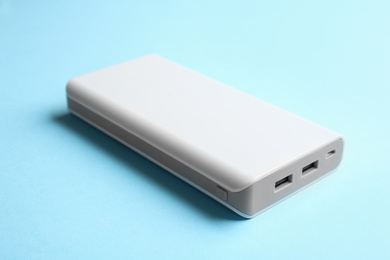 Modern external portable charger on light blue background, closeup