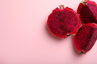 Photo of Delicious cut red pitahaya fruit on light pink background, flat lay. Space for text