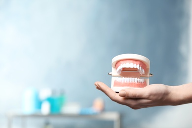 Dentist holding educational model of oral cavity with teeth in clinic, closeup. Space for text