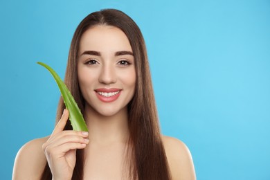 Young woman with aloe vera leaf on light blue background. Space for text