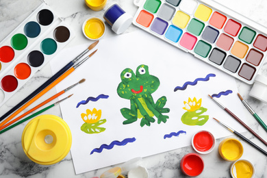 Flat lay composition with child's painting of frog on white marble table