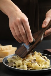 Photo of Woman slicing truffle onto tagliatelle at table, closeup