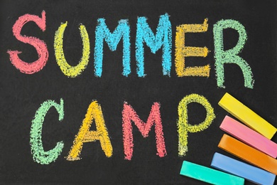 Blackboard with inscription SUMMER CAMP chalked in different colors, closeup