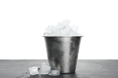 Metal bucket with ice cubes on table against white background