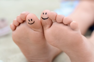 Photo of Woman with smiling faces drawn on toes, closeup of foot