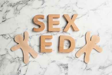 Phrase "SEX ED" made of wooden letters on marble background, flat lay
