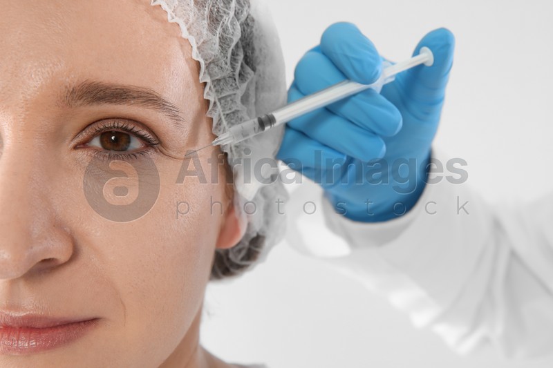 Woman getting facial injection on white background, closeup. Cosmetic surgery concept