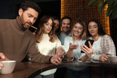 Photo of Friends with drinks and smartphones spending time together in cafe
