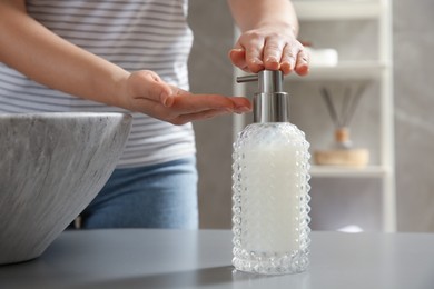 Woman washing hands with liquid soap in bathroom, closeup