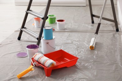 Different paints and decorator's tools near ladder indoors