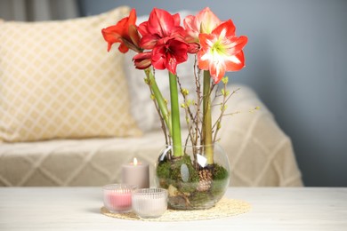 Photo of Beautiful red amaryllis flowers on white table indoors