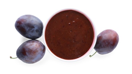 Plum puree in bowl and fresh fruits on white background, top view