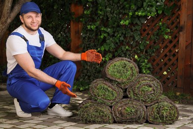 Gardener with grass sod rolls on backyard