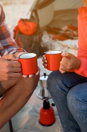 Couple with cups of hot drinks outdoors, closeup. Beach camping