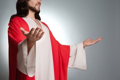 Jesus Christ with outstretched arms on light grey background, closeup