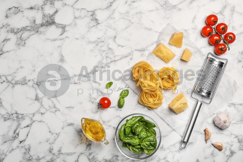 Beautiful composition with raw pasta and ingredients for sauce on marble background, top view