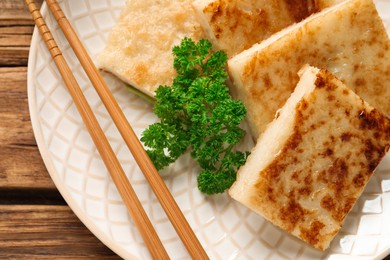 Delicious turnip cake with parsley served on wooden table, top view