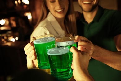 People with beer celebrating St Patrick's day in pub, focus on hands