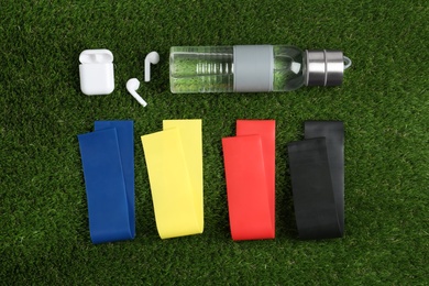 Photo of Flat lay composition with fitness elastic bands on green grass
