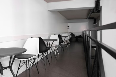 Hostel dining room interior with tables and chairs along white wall