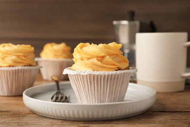 Tasty cupcakes with cream served on wooden table