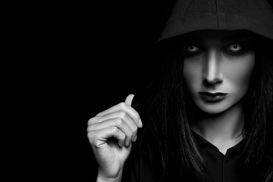 Mysterious witch with spooky eyes on dark background, space for text. Black and white effect