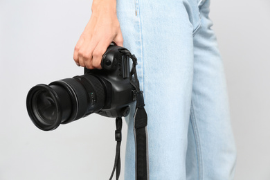 Professional photographer with modern camera on light background in studio, closeup