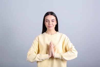 Young woman meditating on grey background. Stress relief exercise